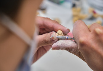 Obraz na płótnie Canvas Dental technician using a brush with ceramic dental implants in his laboratory