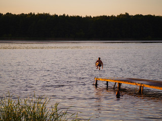 Obraz na płótnie Canvas Jump the guy into the river at sunset