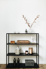 Modern nordic interior design concept. Stylish rack with caskets, cotton branch, vase, candles and...