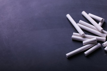 Crayons lie on a black chalkboard, copy space. The concept of school, education and childhood.