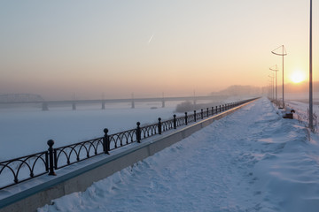 Early in the morning the sun illuminates the embankment covered with snow.