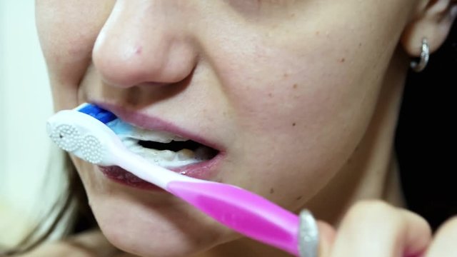 Close-up of beautiful woman brushing her teeth in bathroom front view