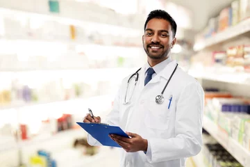 Crédence de cuisine en verre imprimé Pharmacie concept de médecine, de pharmacie et de soins de santé - médecin ou pharmacien indien souriant en blouse blanche avec stéthoscope et presse-papiers sur fond de pharmacie
