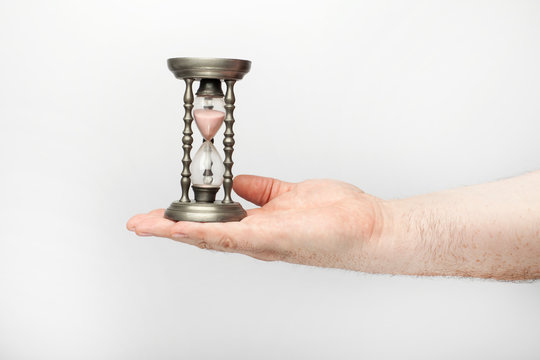 Male hand holds an tin hourglass