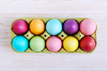 Colored Easter eggs in a pan, on a white wooden table.
