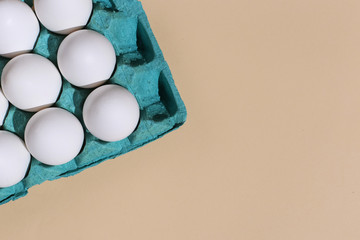 White eggs in a tray on a pastel background.