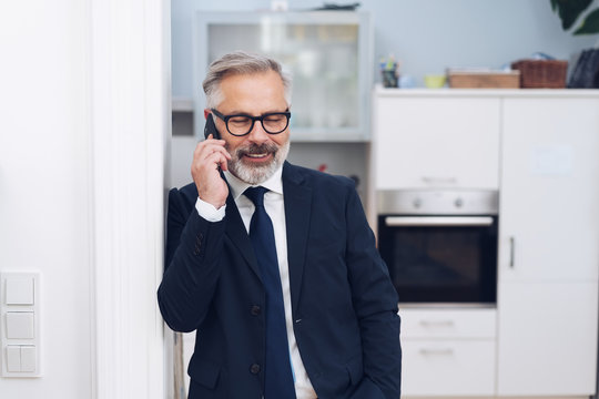 Mature businessman talking by the phone at home
