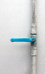 water PVC pipe with blue valve on white concrete wall background