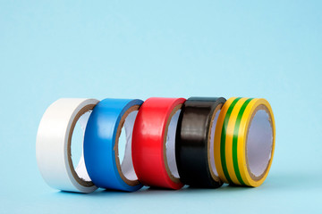 Set of multicolored electrical tape on blue background.