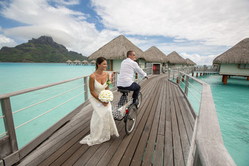 Beautiful wedding couple posing on dock near houses at Bora Bora