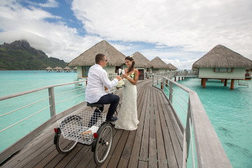 Beautiful wedding couple posing on dock near houses at Bora Bora