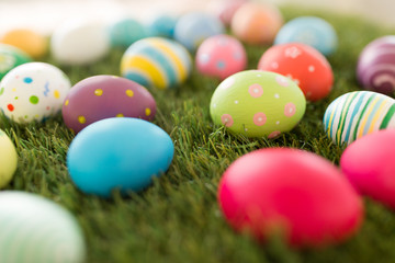 easter, holidays and tradition concept - colored eggs on artificial grass