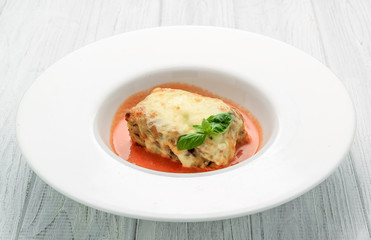 Close-up of a traditional lasagna made with minced beef bolognese sauce topped with basil leafs served