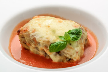 Close-up of a traditional lasagna made with minced beef bolognese sauce topped with basil leafs served