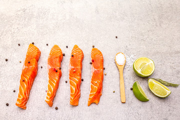 Raw trout (salmon) piece with lime, rosemary, sea salt and pepper mix. Fish on a stone background.