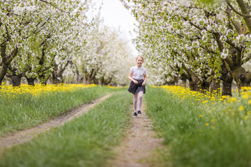 Little girl in blooming apple garden outdoors