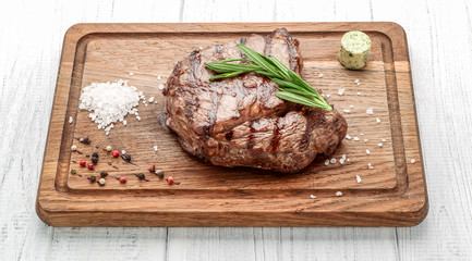 grilled beef steaks with spices on wooden cutting board
