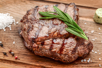 grilled beef steaks with spices on wooden cutting board