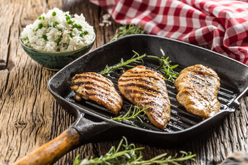 Grilled chicken breast on grilled pan with rice and green peas