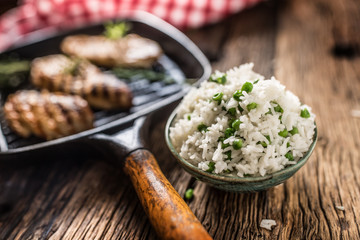 Rice basmati with green peas in bowl and grilled chicken breast in the background