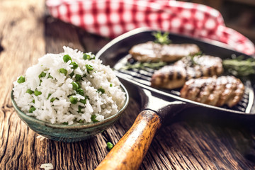 Rice basmati with green peas in bowl and grilled chicken breast in the background
