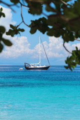Obraz premium A sailboat parked at the beach, turquoise waters and beautiful white sand. 