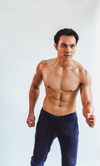 Asian young man playing with muscles and having a six pack is exercising. On the white background
