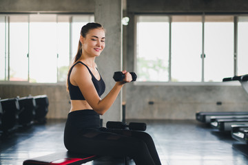 Beautiful girl caucasian is exercising with lifting dumbbell in the gym. Female athletes play a...