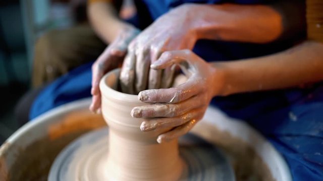 Hands of young couple in love making clay jug on potter's wheel. Sensual footage of people on romantic date. Pottery training, artwork concept. Slow motion.