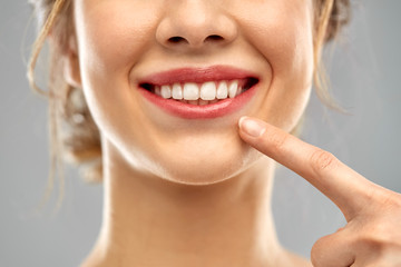 oral care, dental hygiene and people concept - close up of finger pointing to woman face with...
