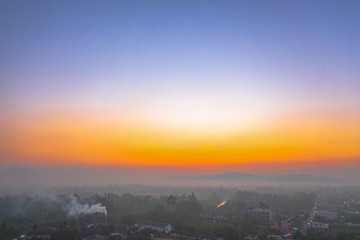 aerial photography smoked from industry blowing during sunrise above mountain in Surat Thani Thailand..