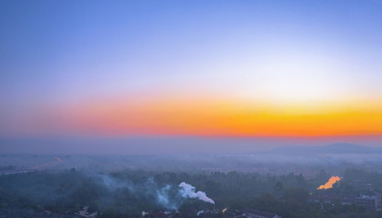 aerial photography smoked from industry blowing during sunrise above mountain in Surat Thani Thailand..