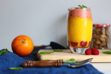 Mango smoothie in glass with raspberry ice cream and mint on wooden.
