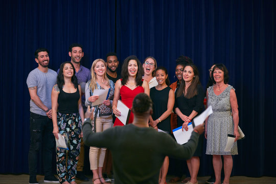 Male conductor directing choir in auditorium