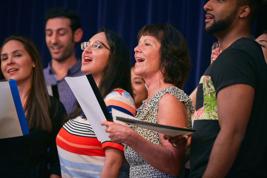 Multi-ethnic choir singers performing on stage in auditorium