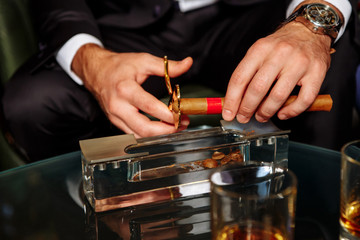 man cuts off the tip of a cigar