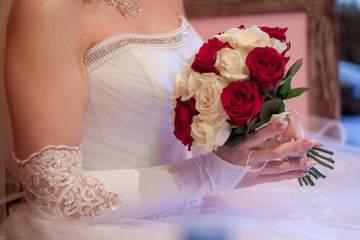 bride holds a bouquet of white and red roses