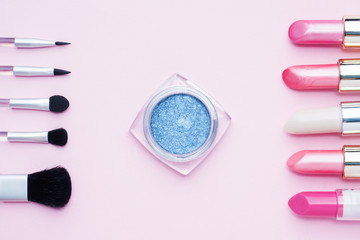 Professional makeup tools. Brushes lipstick blush eye shadow on a pink pastel background with copy space. Flat lay