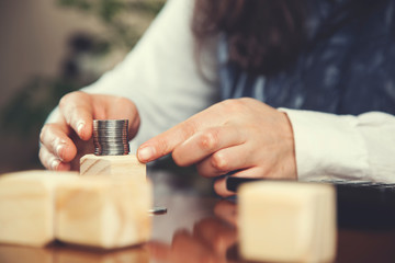 woman hand coins on wooden cubes