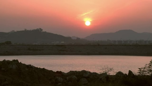 Sunrise at the reservoir,wide angle view. The sun showing up from  mountain  range shining to town and klong katha reservoir early in the morning with twilight sky,4K video timelapse.