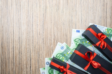 Three black gift box with a bow with euro banknotes on a wooden table. top view, copy space