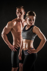 Sporty young couple posing on black background - 249287451