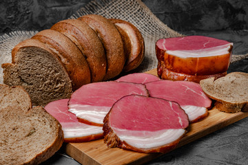 smoked meat and bread with bran on wooden background