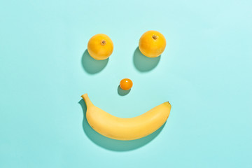 Happy fruit face with banana, tomato and lemons isolated on blue background