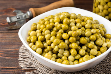 Canned green peas on dark wooden background.