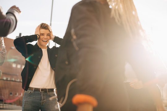Surprised young man with head in hands looking at friend in city