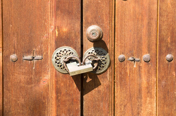 Two old round doorknobs and new padlock on wooden door , Bulgaria