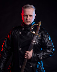 Handsome man in black jacket holding sword