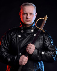 Handsome man in black jacket holding sword