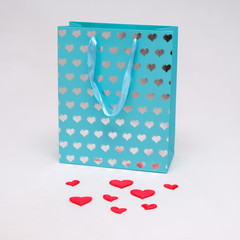 Concept on a white background of Saint Valentine heart of pink color on a package from the store.